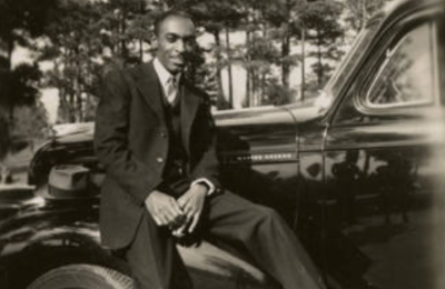 Man in a suit posing on a car